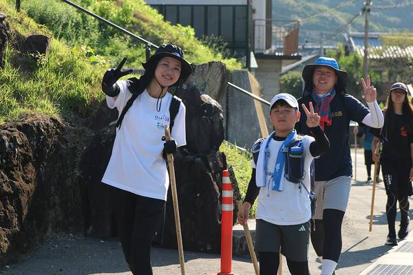 笑顔で手を振りながら道を進む2026年の参加者たち
