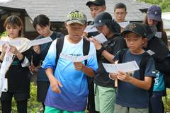 2026年の武者修行：仲間と並び、お経の紙を読む参加者たち